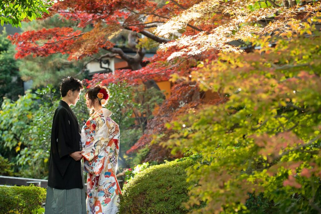 赤く色づく紅葉と和装の新郎新婦