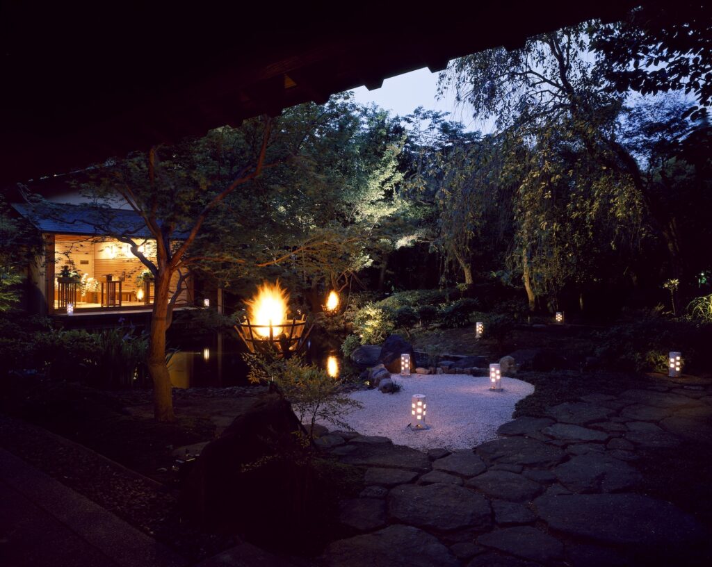 夕暮れ時の陣屋の庭園に灯される篝火